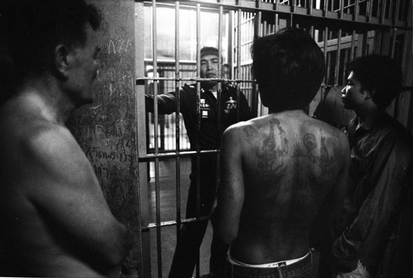 Suspected gangland members await trail at Bangkok Noi's police lock-up. The police officer's nick-name is Rambo he is renowned as Thailand top gang buster. Photograph by Jonathan Taylor.