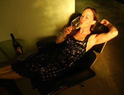 Carrie Graber sipping some of the LXV wine that bears her painting on its label. Self-portrait by the artist.